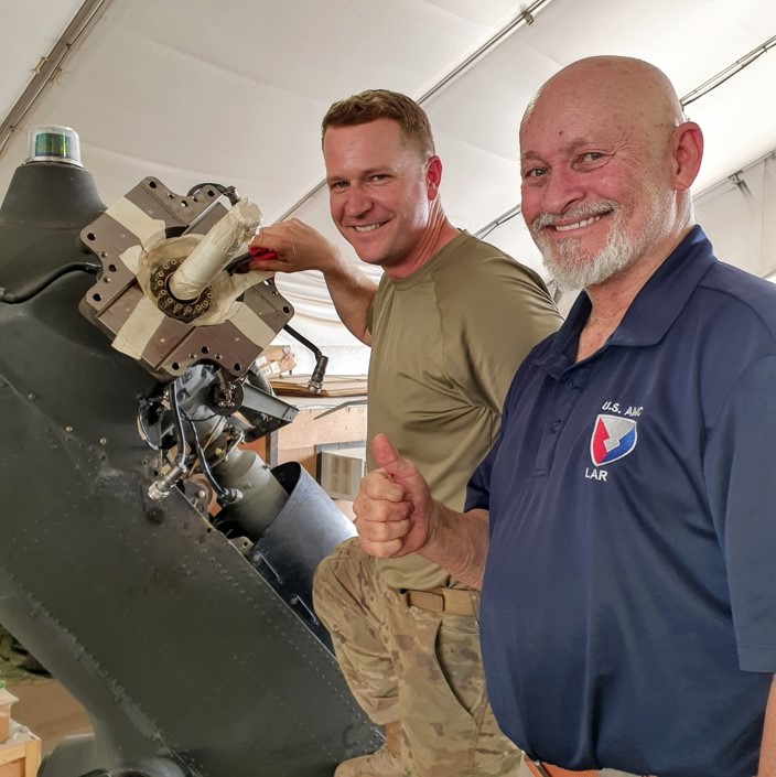 Charles “Chazz” Pope (right) observes an aviation mechanic working on the tail rotor assembly.